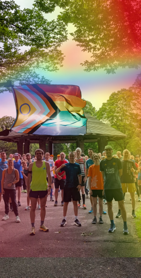 Groep mensen in sportieve kleding, en face, in een boomrijke omgeving. Er wappert een grote inclusieve (lhbtqi+) vlag.